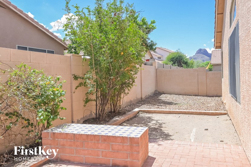 a backyard with a brick retaining wall and a tree