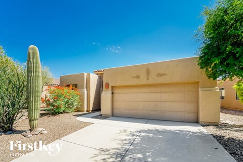 A house with a garage door and a cactus in front.