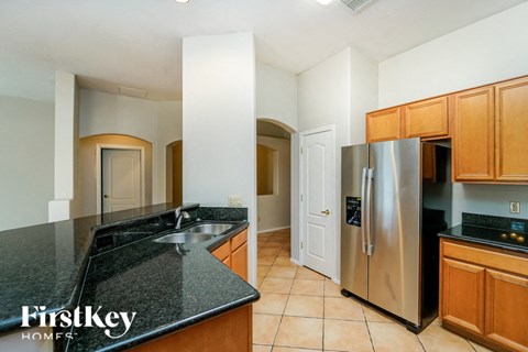 A kitchen with a black granite counter top and wooden cabinets.