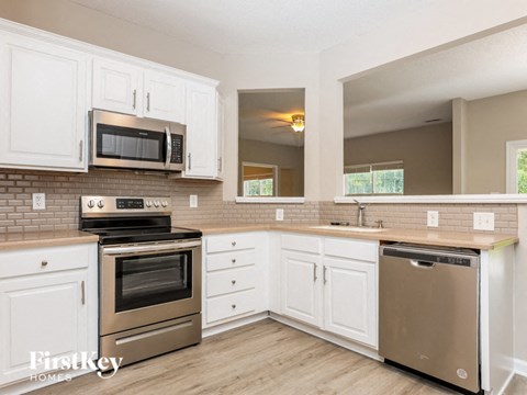 A kitchen with white cabinets and a stainless steel oven.