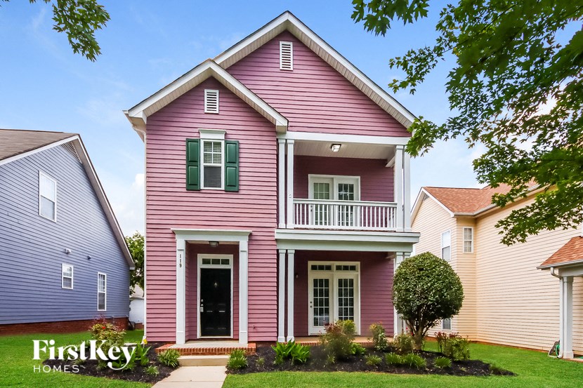 A pink house with a black door and green shutters.