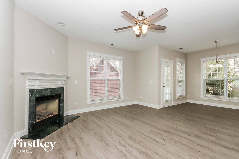 A spacious living room with a fireplace and a ceiling fan.