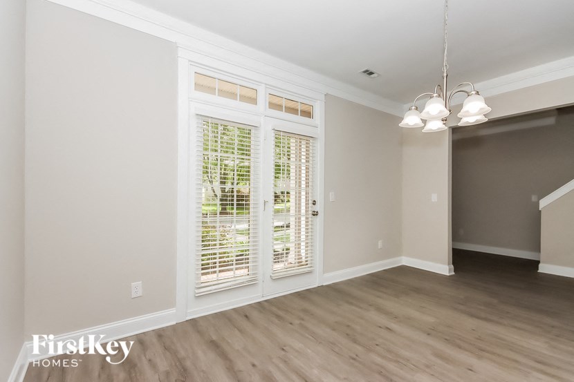 A room with a window covered by white blinds and a wooden floor.
