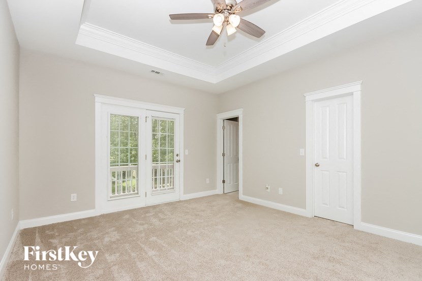 A spacious room with a ceiling fan and a door leading to another room.