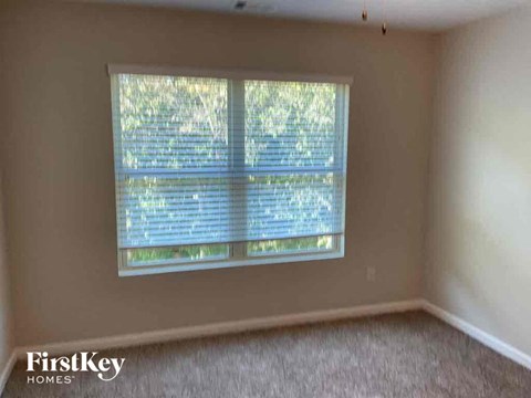 a bedroom with a window and a carpeted floor
