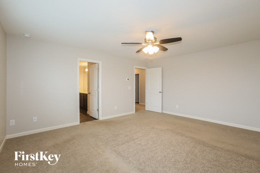 A spacious room with a carpeted floor and a ceiling fan.