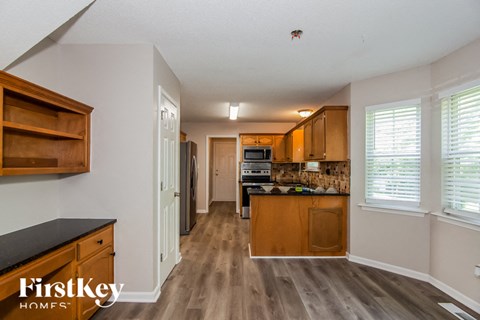 a kitchen with wood floors and white walls and wooden cabinets