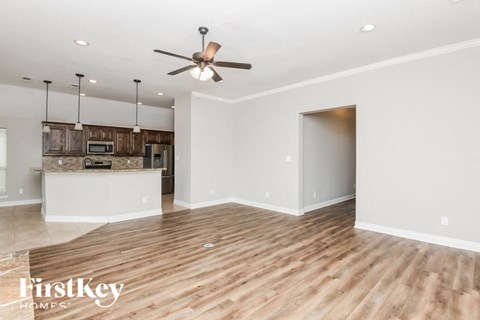an empty living room and kitchen with a ceiling fan