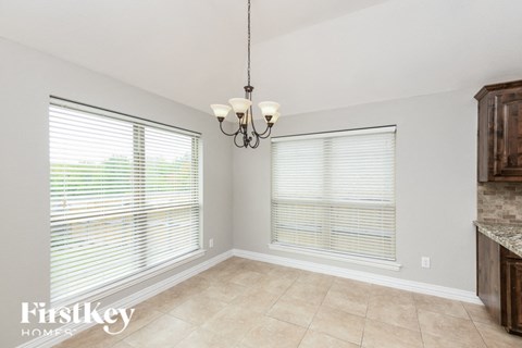 a dining room with two windows and a chandelier