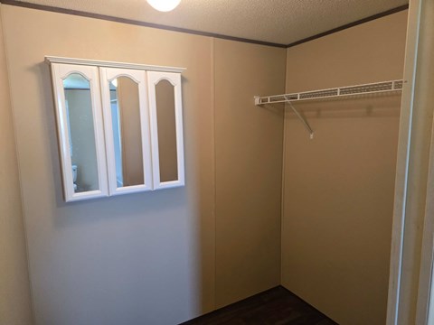 A small, empty room with a white shelf and a window.