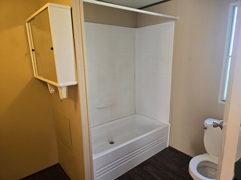 A white bathroom with a toilet and a walk-in shower.