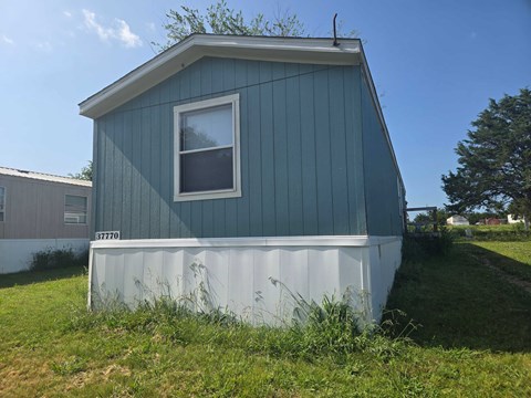 A blue house with a white window and a white garage door.