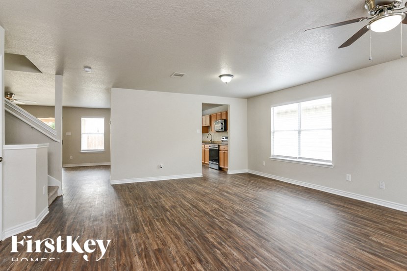 A spacious room with wooden floors and a ceiling fan.