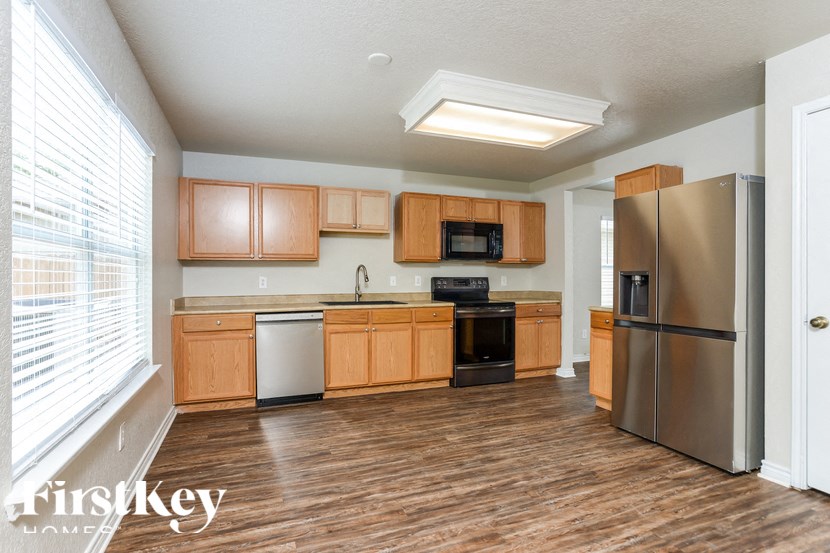 A kitchen with wooden cabinets and a stainless steel refrigerator.