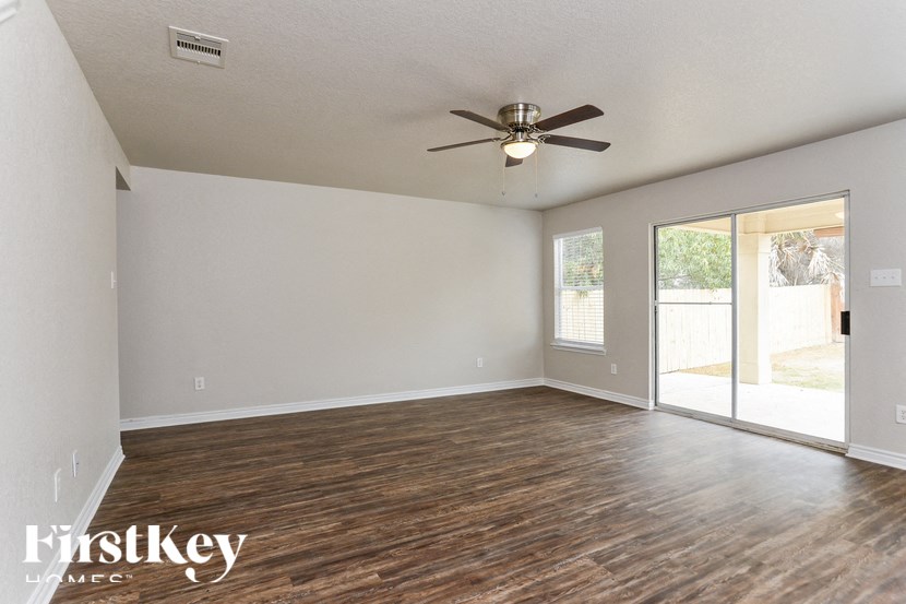 A room with a ceiling fan and sliding glass doors.
