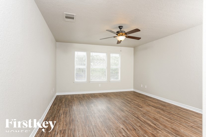 A room with a ceiling fan and wooden flooring.