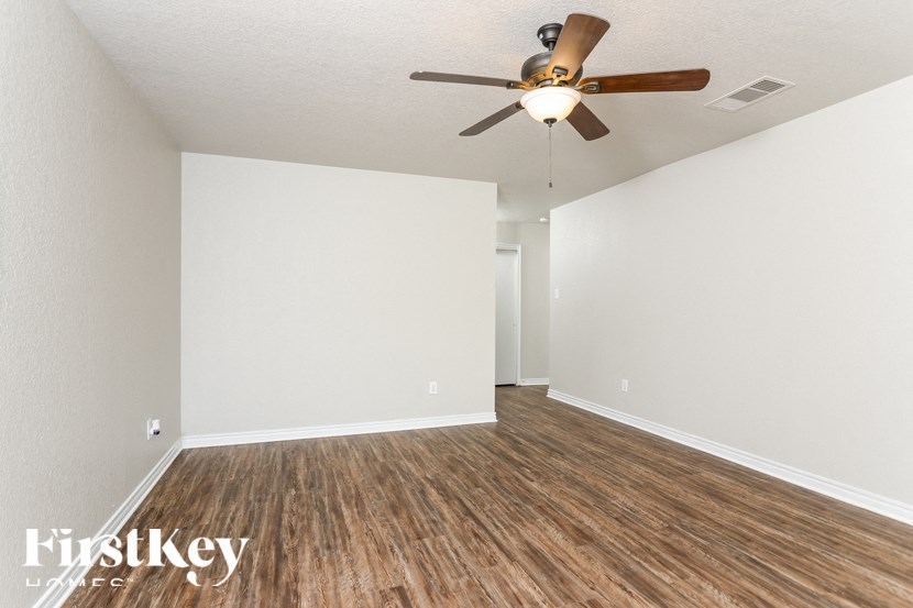 A room with a ceiling fan and wooden flooring.