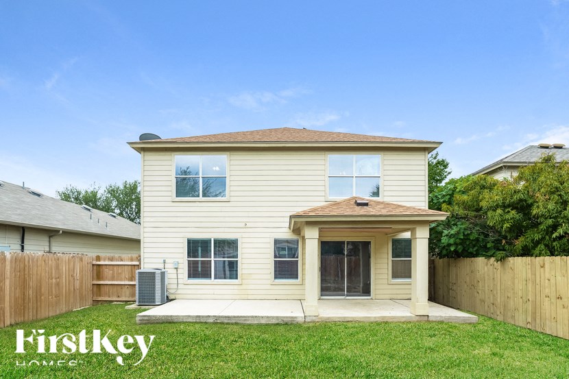 A beige house with a brown fence and a green lawn in front.