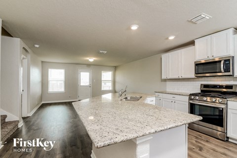 a kitchen with white cabinets and a marble counter top