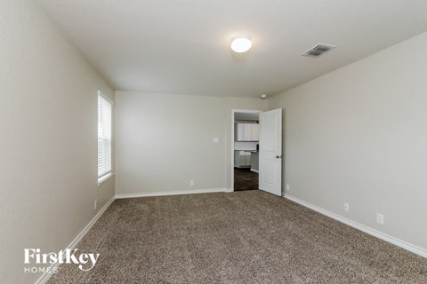 a spacious living room with carpet and a door to the kitchen