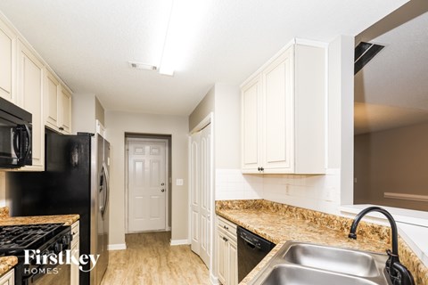 A kitchen with a sink, stove, and cabinets.