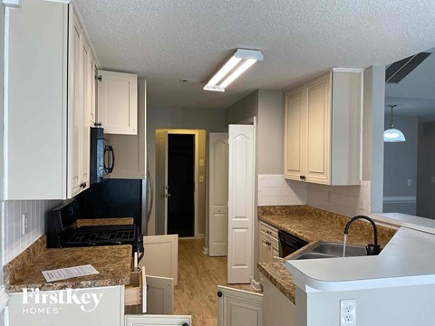 A kitchen with granite countertops and white cabinets.