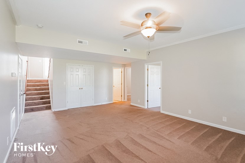 a empty living room with a ceiling fan and a staircase