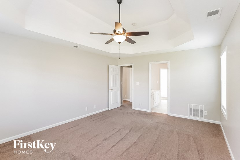 a spacious living room with white walls and a ceiling fan