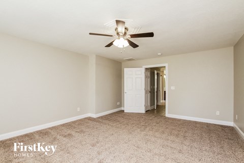 a living room with a ceiling fan and a door to a hallway