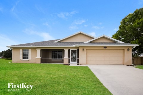 a beige house with a lawn and a driveway