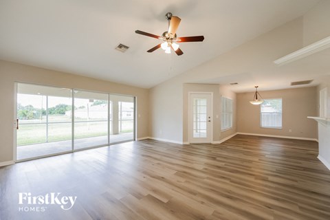 an empty living room with wood floors and a ceiling fan