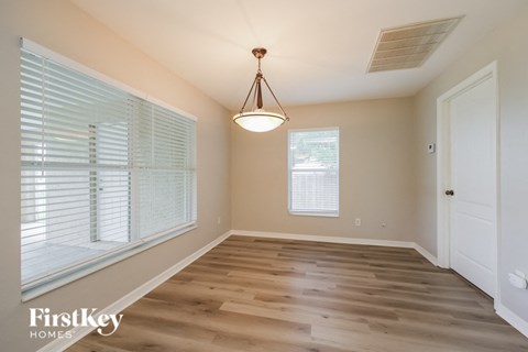 an empty dining room with wood flooring and a large window