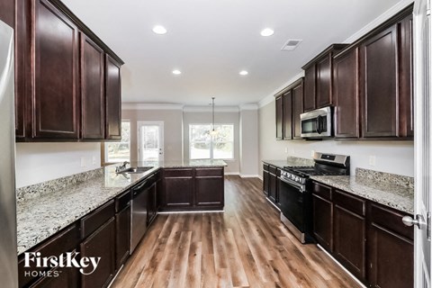 A kitchen with dark wood cabinets and a granite countertop.