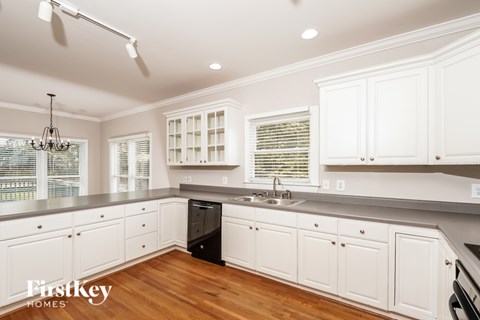 A kitchen with white cabinets and a black dishwasher.