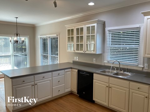 A kitchen with a black trash can and a sink.