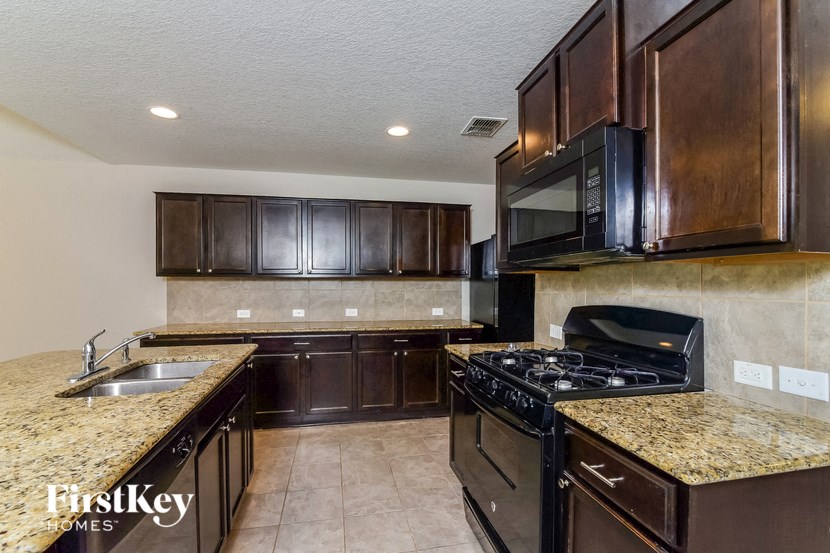 a kitchen with dark wood cabinets and granite counter tops and a stove and sink