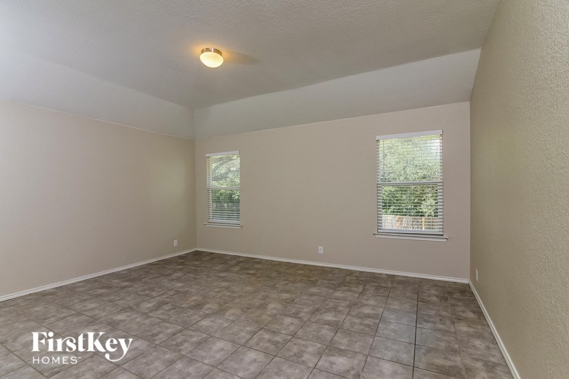 the living room of an empty house with a tile floor and two windows