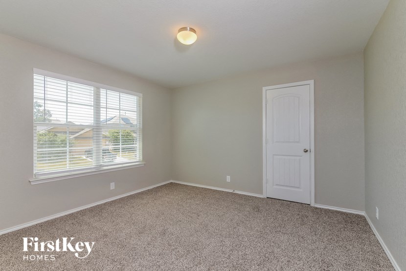 a bedroom with carpet and a white door and window