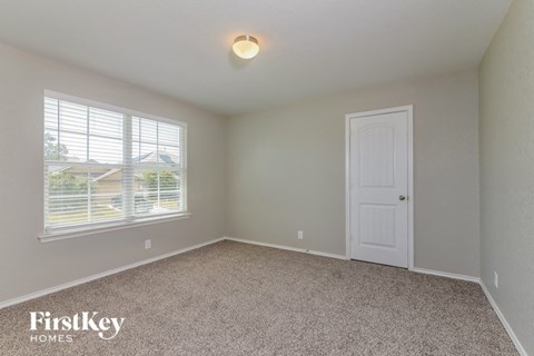 a bedroom with carpet and a white door and window