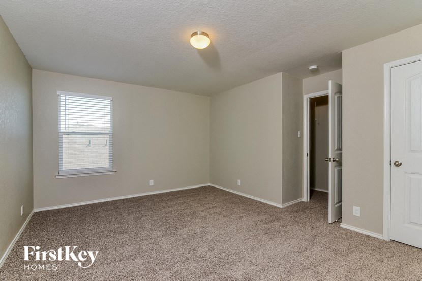 the spacious bedroom with carpeted flooring and a door to the bathroom