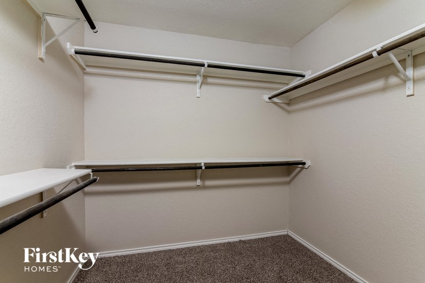 a walk in closet with empty shelves and a white wall