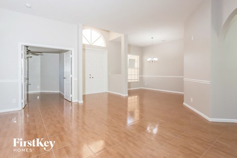 A spacious room with wooden flooring and white walls.