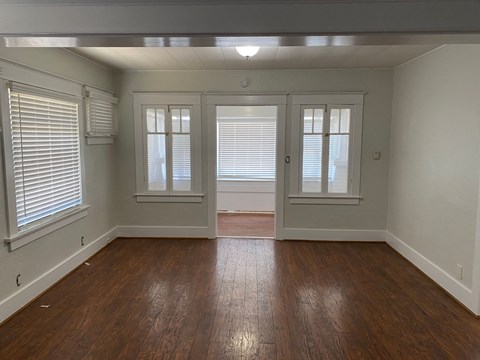 an empty living room with a hard wood floor and windows
