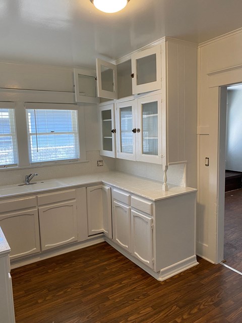a kitchen with white cabinets and a wooden floor