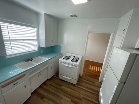 A kitchen with white cabinets and a white fridge.