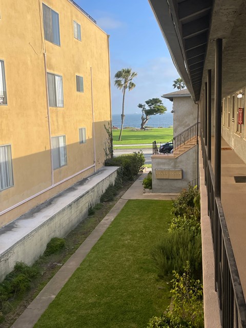 A yellow building with a balcony overlooking a green lawn.