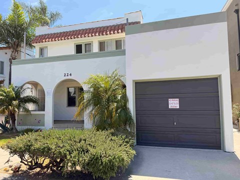 A building with the number 224 on it has a closed black garage door.