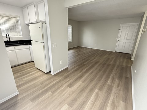 A kitchen with white cabinets and a fridge is shown.