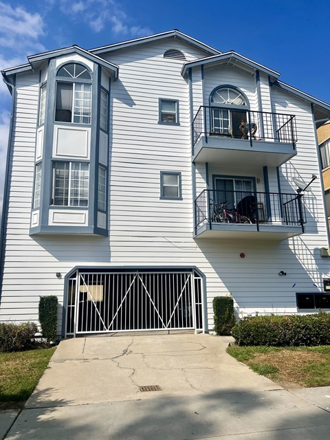 A white two-story apartment building with a black gate in front.