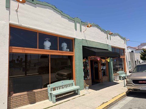 A storefront with a green bench in front of it.